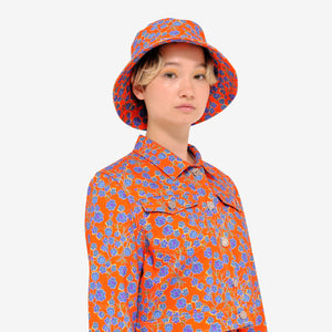 Model wearing Crimson Rose cropped cotton drill jacket and bucket hat with orange and blue floral print. Photography Rowan Corr.