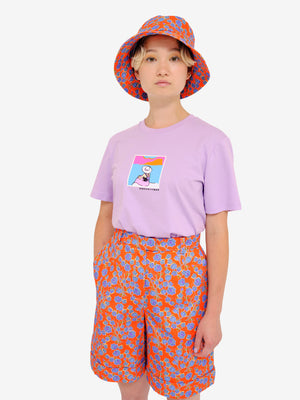 Model wearing Crimson Rose Es Vedrà lilac T-shirt, cropped cotton drill culottes and bucket hat with orange and blue floral print. Photography Rowan Corr.